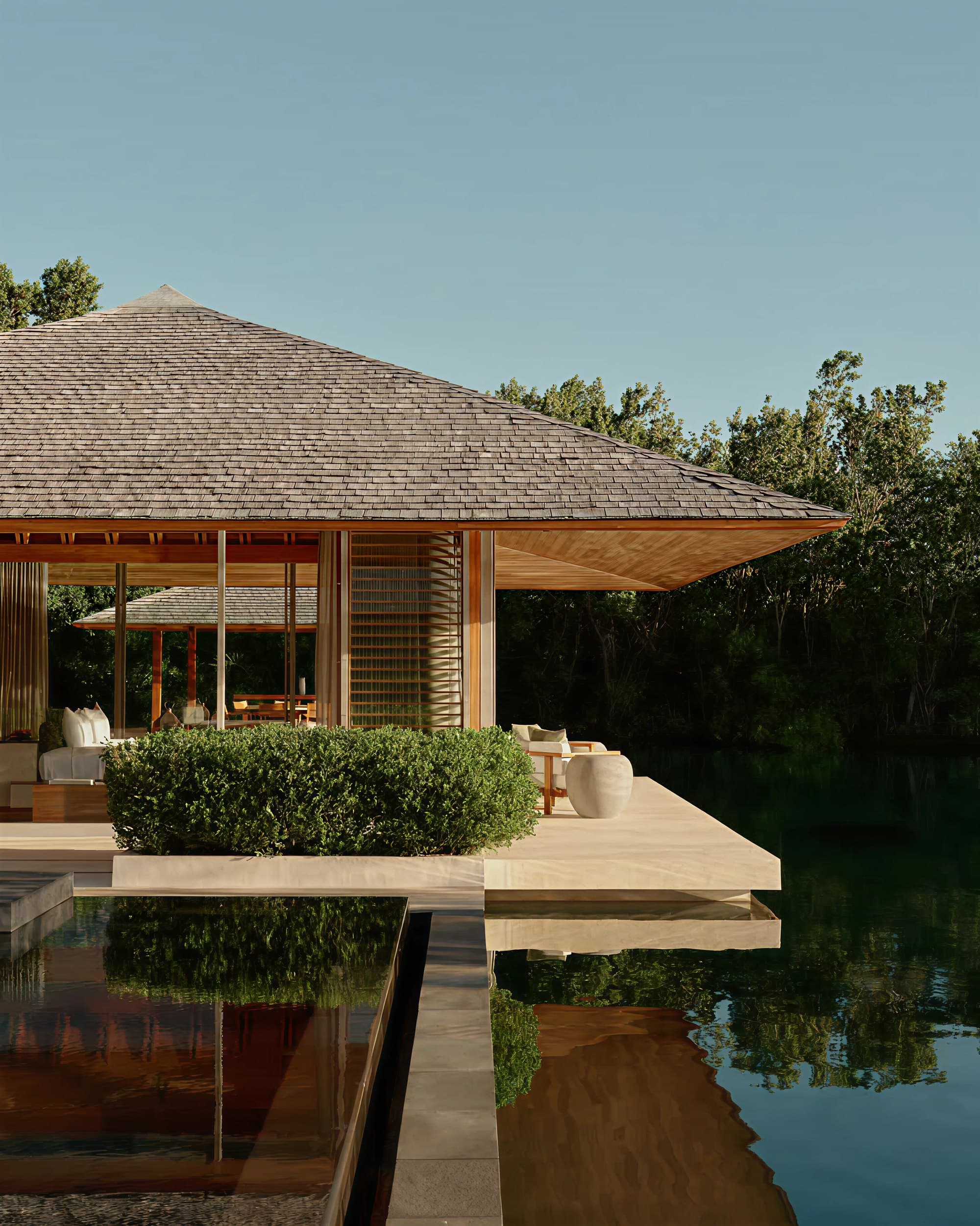 A timber pavilion beside a reflecting pool at dusk